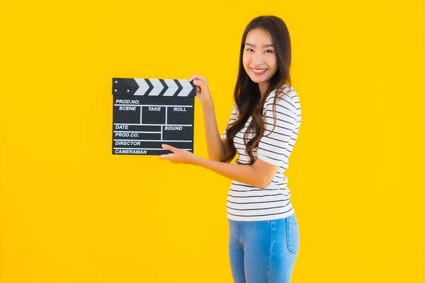 年轻美丽的亚洲女子在黄色隔离背景下展示拍片板 — 图库照片