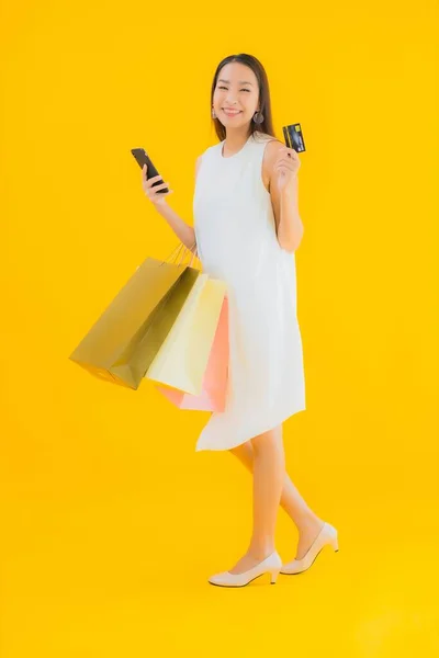 亚洲年轻貌美的女子 背负着黄色背景的零售店购物袋 — 图库照片
