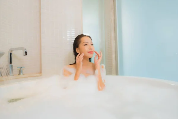 在浴室内部的浴缸里 年轻美丽的亚洲女人在浴缸里放松地笑着 — 图库照片