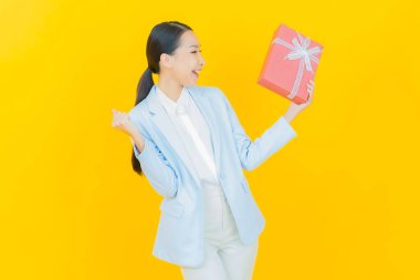 Güzel bir Asyalı kadının portresi. Arka planda kırmızı hediye kutusuyla gülümsüyor.