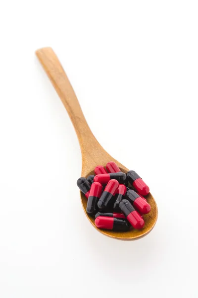 Pillola compressa su cucchiaio di legno isolato su sfondo bianco — Foto Stock