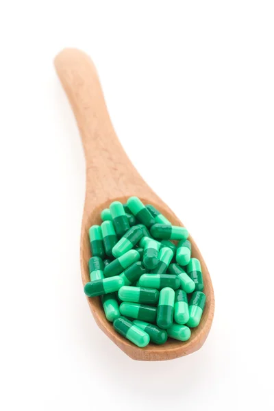 Pillole di droga su cucchiaio di legno isolato su sfondo bianco — Foto Stock