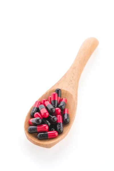 Tabletki leku na drewnianą łyżką na białym tle — Zdjęcie stockowe
