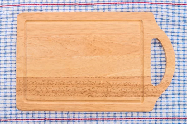 Wood cutting board on tablecloth — Stock Photo, Image