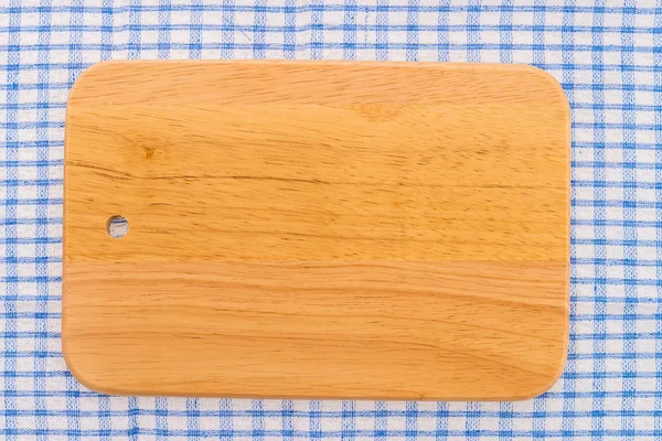 Wood cutting board on tablecloth — Stock Photo, Image