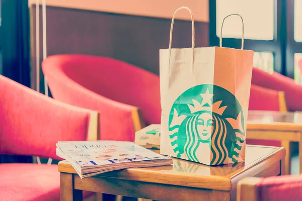 Bolso de papel Starbuck sobre mesa de madera en tienda starbuck — Foto de Stock