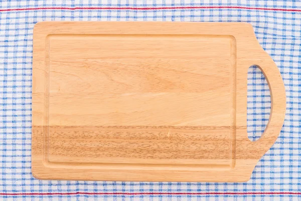 Wood cutting board on tablecloth — Stock Photo, Image