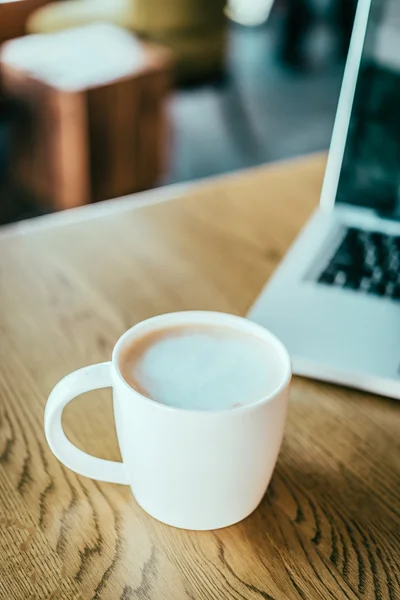 Tazza di caffè, laptop in caffetteria — Foto Stock