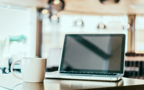 Coffee cup, laptop in coffee shop — Stock Photo, Image
