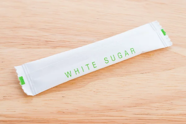 Saco de açúcar branco no fundo de madeira — Fotografia de Stock
