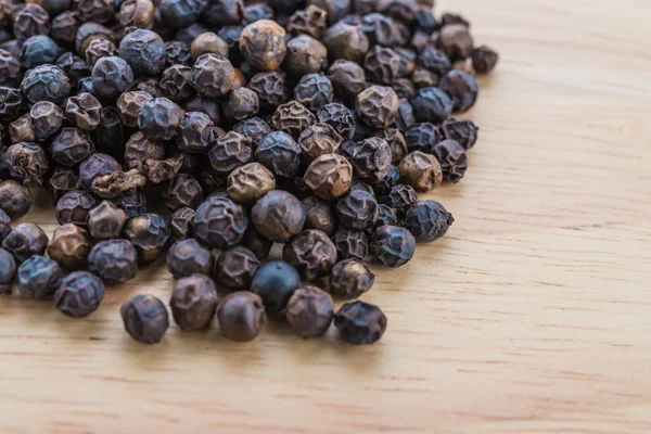 Black pepper on wood background — Stock Photo, Image