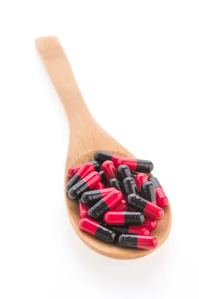 Pillole di droga su cucchiaio di legno isolato su sfondo bianco — Foto Stock