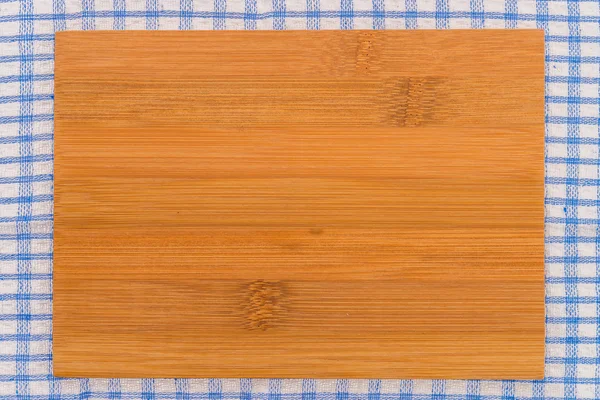 Wood cutting board on tablecloth — Stock Photo, Image