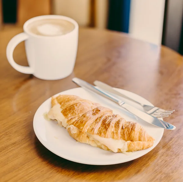 Croissant a kafe pohár — Stock fotografie