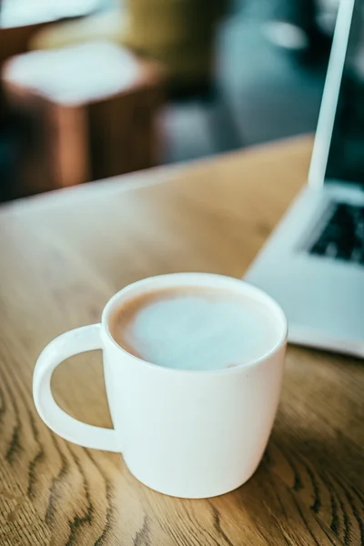 Tazza di caffè con computer portatile in caffetteria — Foto Stock