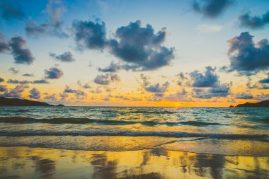 Bulutlu gökyüzü üzerinde sahilde günbatımı