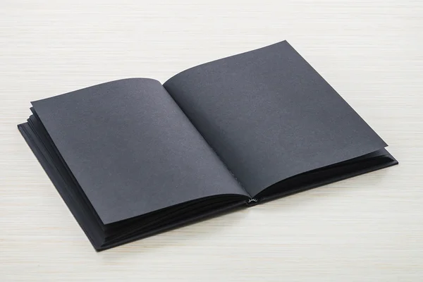木材的背景上的黑色笔记本 — 图库照片