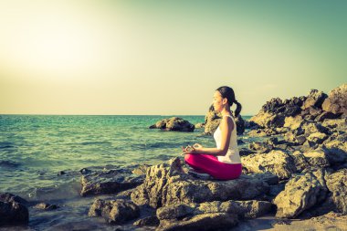 Kumsalda yoga yapan bir kadın.