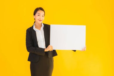 Güzel bir portre. Genç Asyalı kadın, sarı izole edilmiş arka planda boş beyaz tahta gösteriyor.