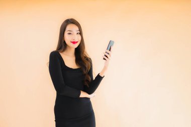 Güzel Asyalı genç bir kadının portresi mutlu bir şekilde gülümsüyor renkli arka planda akıllı cep telefonu kullan