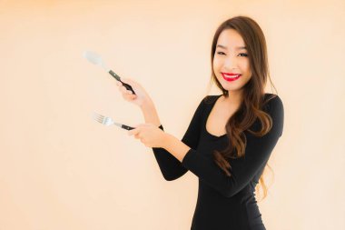 Kaşığı ve çatalı olan güzel Asyalı bir kadının portresi izole edilmiş renkli arka planda yemeye hazır.