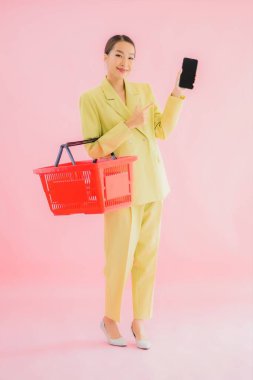 Renkli arka planda süpermarketten alınmış market sepetiyle güzel bir Asyalı kadın portresi.