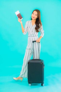 Güzel Asyalı bir kadının portresi. Bavul pasaportu ve biniş kartı mavi arka planda seyahat için hazır.