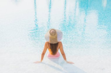 Güzel bir Asyalı kadın portresi. Tatil gezisinde deniz manzaralı açık havuz etrafında rahatça yüzebiliyor.