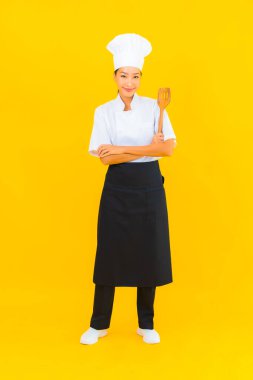 Sarı izole arkaplanda spatulası olan güzel, genç Asyalı şef kadın portresi.