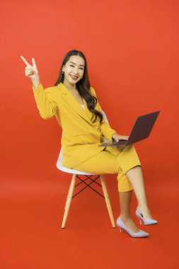 Portre güzel genç iş kadını Asyalı kadın kırmızı arka planda bilgisayar bilgisayarı kullanıyor