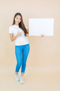 Güzel bir Asyalı kadın portresi. Krem arka planda boş beyaz ilan panosu kağıdı gösteriyor.