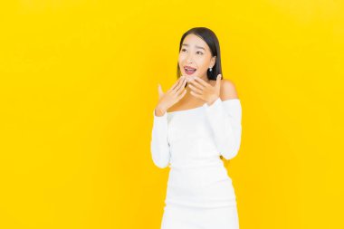 Portre güzel genç iş kadını gülümseyen ve eylem sarı arka planlı Asyalı kadın