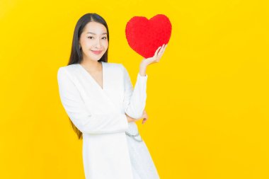 Portre güzel Asyalı genç kadın gülümsüyor kalp yastığı şeklinde renk arkaplan