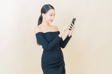 Renkli arka planda akıllı cep telefonuyla güzel Asyalı kadın gülümsemesi