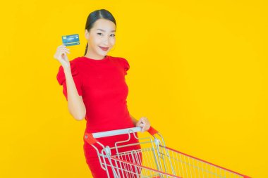 Renkli arka planda süpermarketten alınmış market sepetiyle gülümseyen güzel Asyalı kadın portresi.