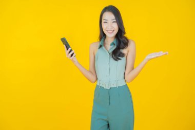 Renkli arka planda akıllı cep telefonuyla güzel Asyalı kadın gülümsemesi