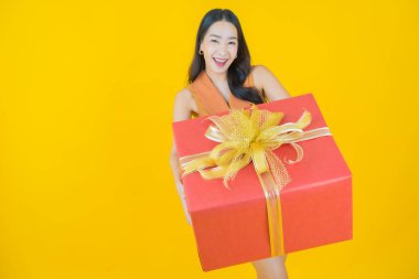 Güzel bir Asyalı kadının portresi. Arka planda kırmızı hediye kutusuyla gülümsüyor.