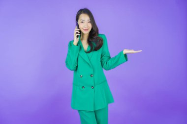 Renkli arka planda akıllı cep telefonuyla güzel Asyalı kadın gülümsemesi