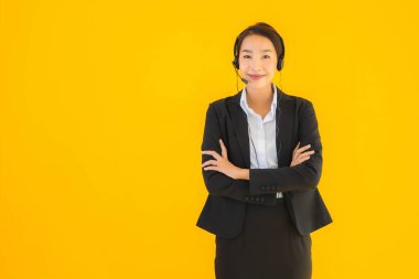 Portre güzel genç Asyalı kadın kulaklık ya da çağrı merkezi için kulaklık ya da tele pazarlama sarı izole arka planda.