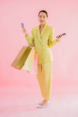 Renkli arka planda alışveriş çantası taşıyan güzel Asyalı iş kadını portresi.