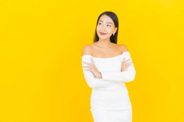 Portre güzel genç iş kadını gülümseyen ve eylem sarı arka planlı Asyalı kadın