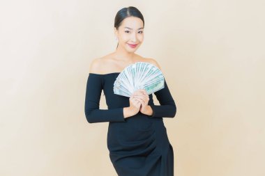 Asyalı güzel bir kadının portresi. Renkli arka planda bol para ve parayla gülümsüyor.