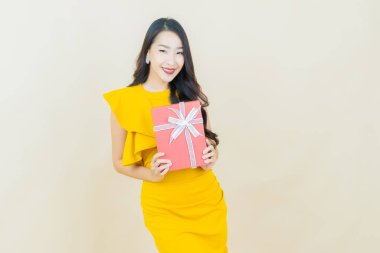 Güzel bir Asyalı kadının portresi. Arka planda kırmızı hediye kutusuyla gülümsüyor.