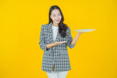 Güzel Asyalı bir kadının portresi. Arka planda boş tabak tabağıyla gülümsüyor.