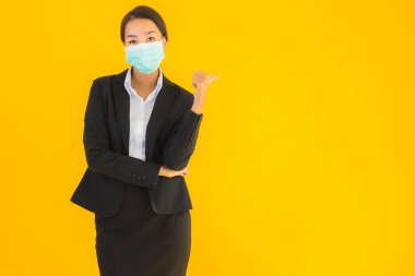 Güzel genç iş kadını portresi Korunmak için maske takıyor 19 koronavirüs sarı izole arka planda