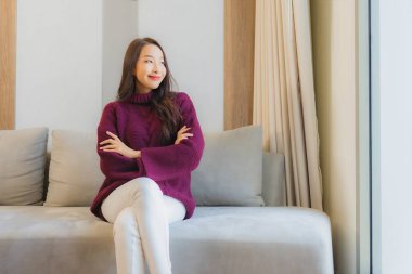 Portre güzel Asyalı kadın gülümsemesi. Oturma odasındaki kanepede rahatla.