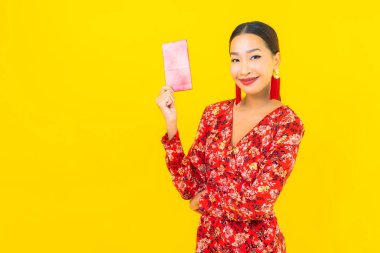 Sarı arka planda kırmızı zarfları olan güzel Asyalı kadın portresi.