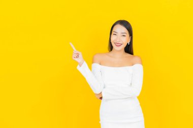 Portre güzel genç iş kadını gülümseyen ve eylem sarı arka planlı Asyalı kadın