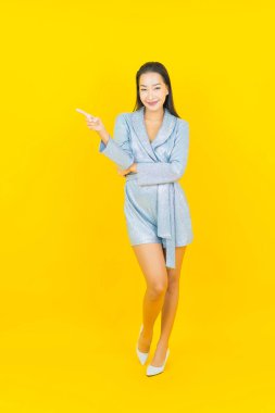 Asyalı güzel bir kadının portresi. Sarı arka planda hareketli gülümsüyor.