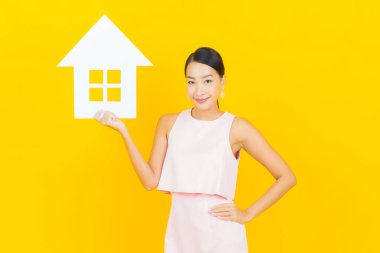 Sarı arka planda ev ya da kağıt tabelalı güzel Asyalı kadın portresi